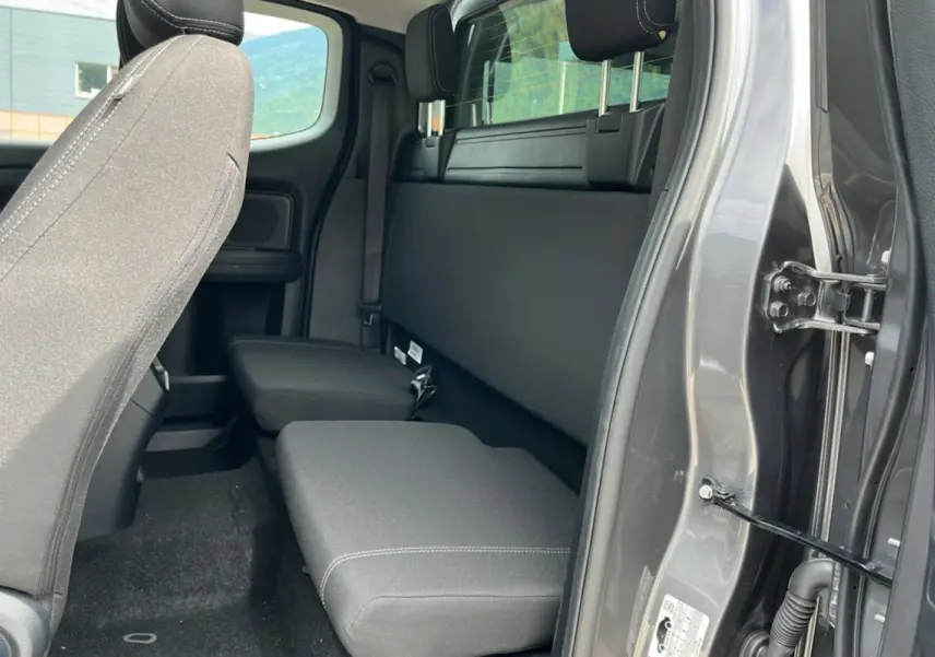 Vue intérieure côté droit du Ford Ranger gris carbone 2025, montrant la banquette arrière Supercab et l'ouverture de porte.