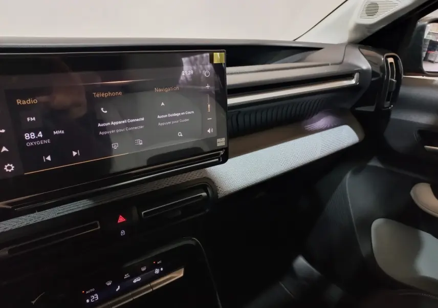 Vue intérieure côté passager du tableau de bord gris foncé de la Citroën C3 hybride avec écran tactile central lumineux.