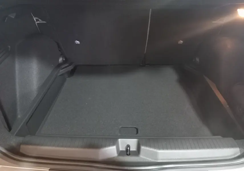 Vue intérieure du coffre spacieux et vide de la Citroën C3 hybride gris foncé, avec banquette arrière rabattue.