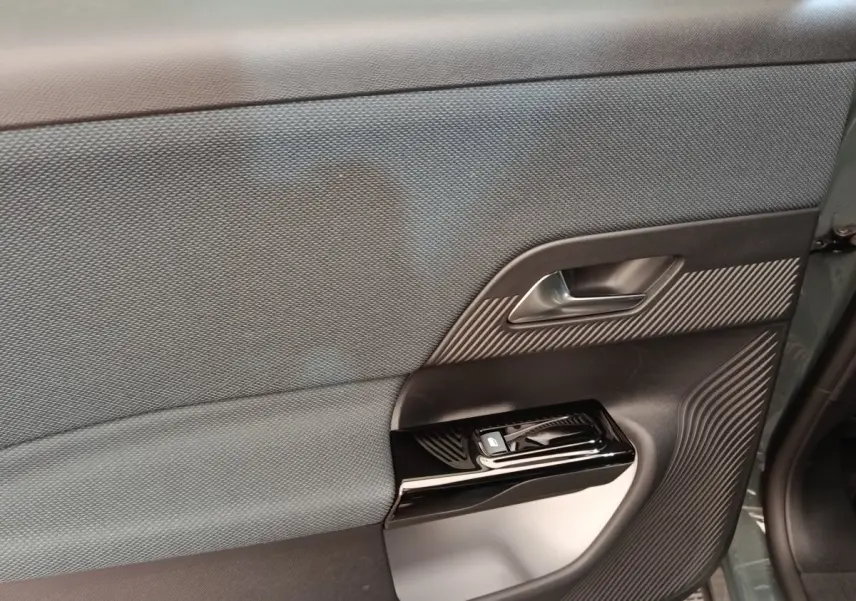 Détail de la porte intérieure côté gauche de la Citroën C5 hybride 2026 avec insert texturé et commande de vitre noire.