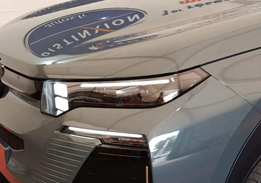 Gros plan sur le phare avant droit d'une Citroën C5 hybride vert clair avec détails LED et carrosserie brillante.