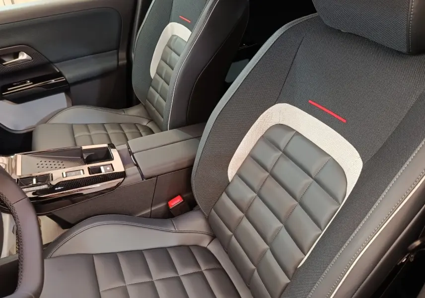 Gros plan sur les sièges avant en cuir noir et tissu gris avec surpiqûres et détails rouges d'une Citroën C5 hybride.