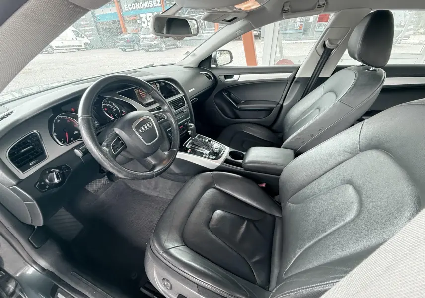 Vue intérieure côté conducteur de l'Audi A5 Sportback 2009 avec sièges cuir noir et tableau de bord moderne.