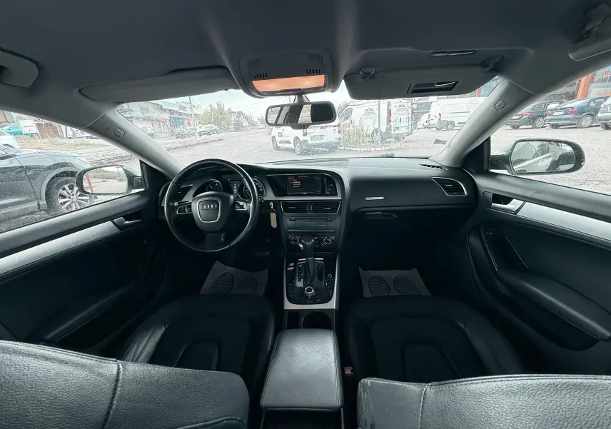 Vue intérieure avant de l'Audi A5 Sportback 2009 avec tableau de bord et sièges en cuir noir.
