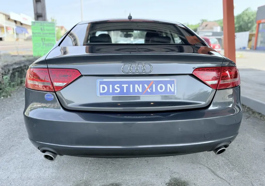 Vue arrière d'une Audi A5 Sportback gris dauphin de 2009 avec feux rouges et double sortie d'échappement visible.