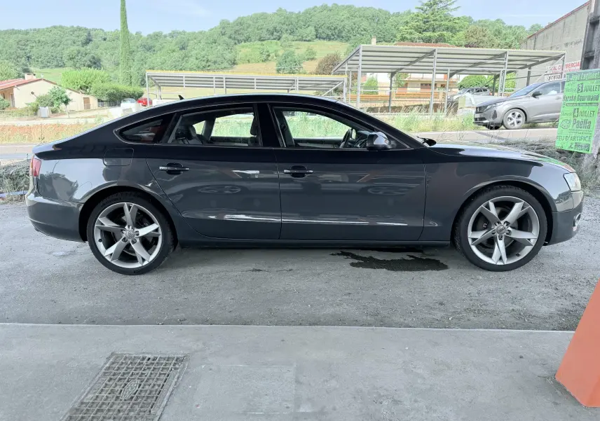 Audi A5 Sportback gris dauphin vue de profil côté gauche, avec jantes alliage 5 branches et silhouette élégante.
