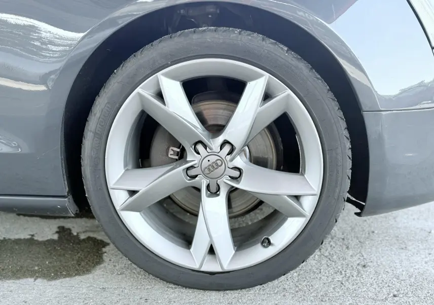 Gros plan sur la roue avant droite de l'Audi A5 Sportback gris dauphin, mettant en valeur la jante en alliage à cinq branches.
