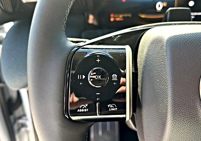 Gros plan sur les commandes multifonctions du volant côté gauche du Citroën C5 Aircross hybride blanc et noir.