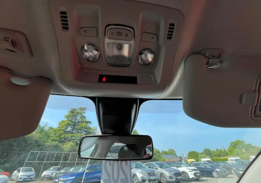 Vue intérieure du plafond et du rétroviseur central d'une Citroën C3 noire 2023, avec pare-soleil baissé et ciel dégagé visible.