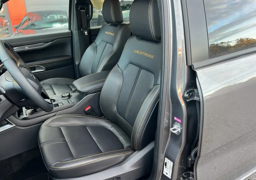 Vue intérieure côté conducteur du Ford Ranger 2025 gris carbone, sièges en cuir noir avec surpiqûres jaunes et logo Wildtrak brodé.