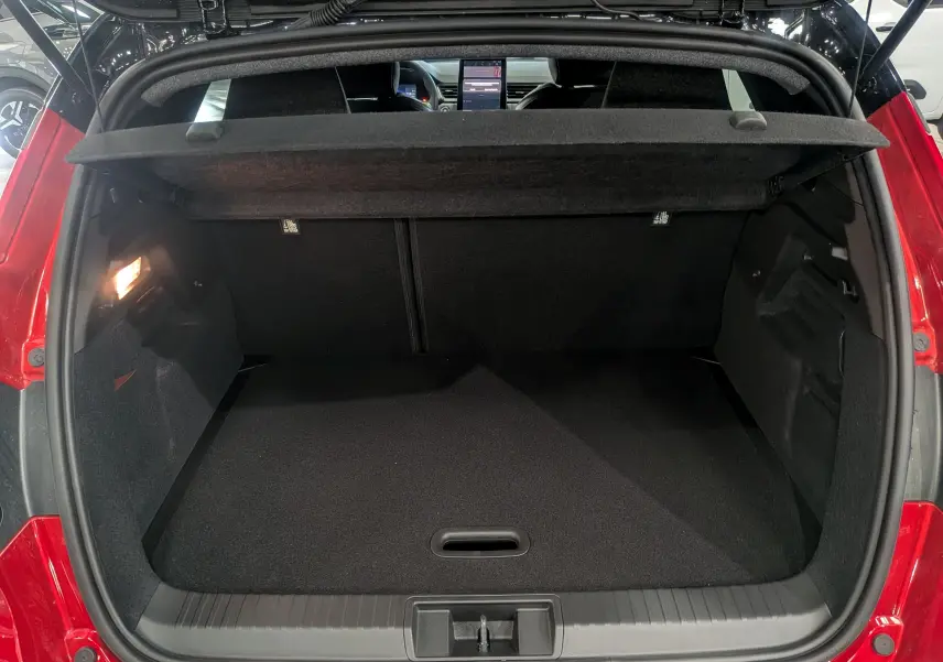Coffre ouvert vu de l'arrière du Renault Captur E-TECH rouge Flamme avec toit noir, montrant un espace de chargement vide et lumineux.