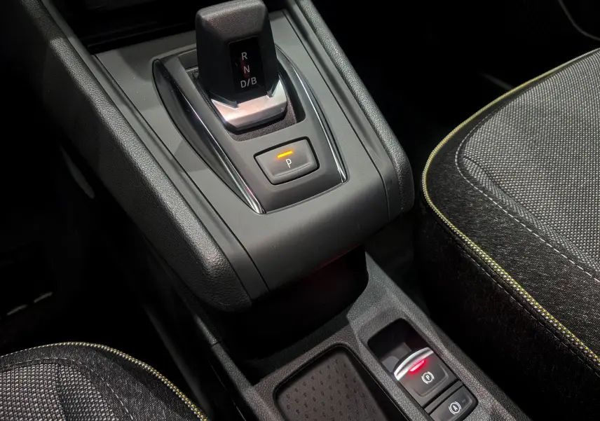Gros plan sur la console centrale du Renault Captur hybride 2025, montrant le levier de vitesse automatique et les sièges en tissu noir.