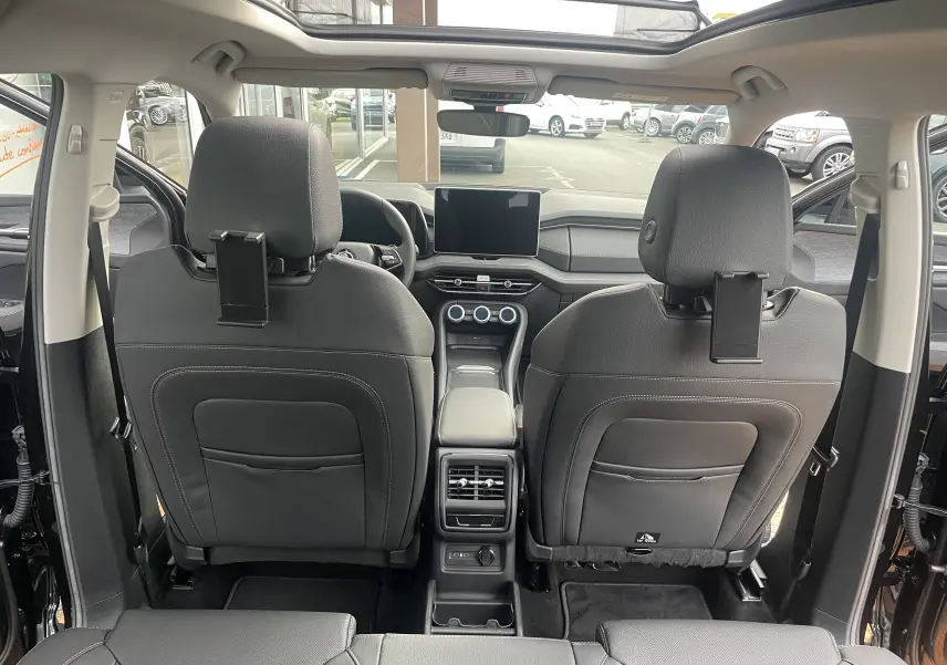 Vue intérieure arrière du Skoda Kodiaq noir métal 2024 montrant les sièges avant en cuir noir et la console centrale avec écran tactile.