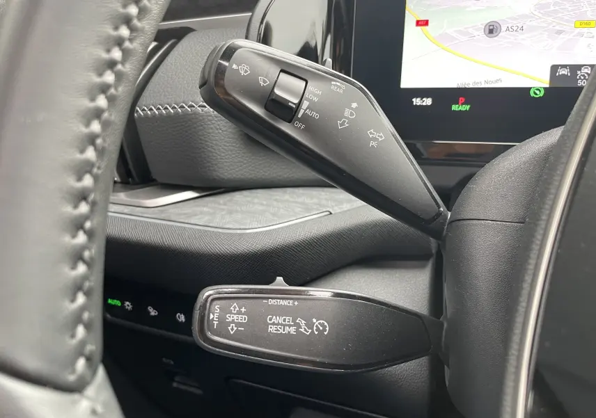 Gros plan sur les commandes au volant du Skoda Kodiaq noir métal 2024, avec affichage GPS et réglages de vitesse visibles.