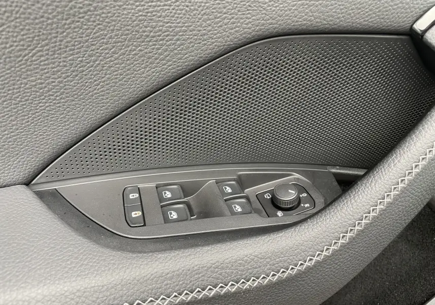 Gros plan sur les commandes de lève-vitres et réglage des rétroviseurs côté conducteur du Skoda Kodiaq noir métal 2024.