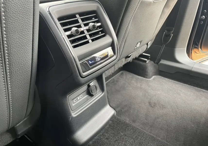 Détail de la console arrière avec sorties d'air et ports USB dans un Skoda Kodiaq noir métal, vue côté gauche arrière.