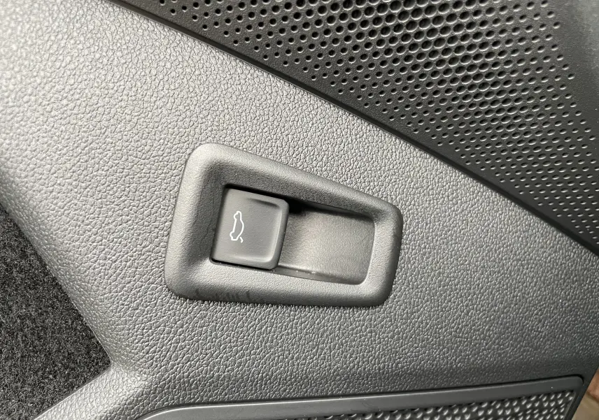 Bouton d'ouverture de coffre intégré dans le panneau intérieur noir texturé d'un Skoda Kodiaq 2024.
