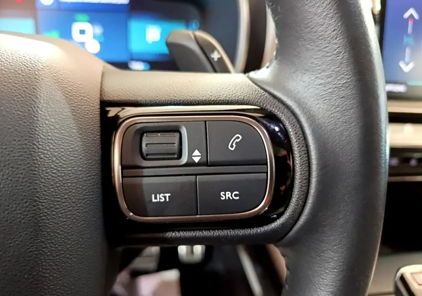 Gros plan sur les commandes gauche du volant cuir noir du Citroën C5 Aircross Hybrid 225 ë-EAT8 Shine Pack.