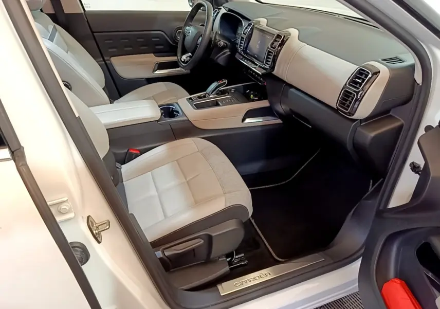 Vue intérieure côté conducteur du Citroën C5 Aircross blanc, montrant sièges bicolores et tableau de bord moderne avec écran tactile.