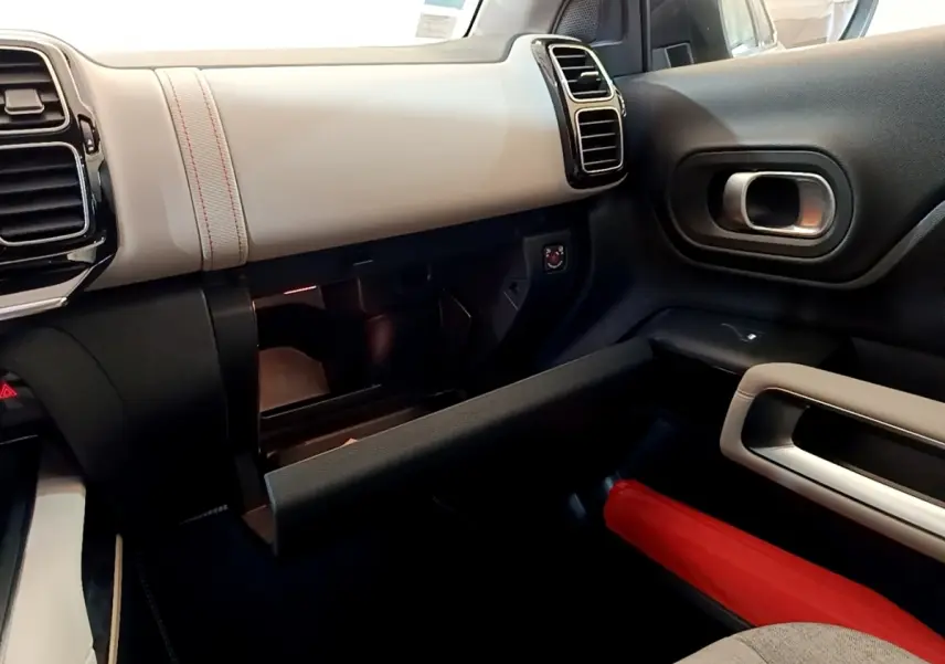 Intérieur côté passager du Citroën C5 Aircross Hybrid blanc, tableau de bord clair et boîte à gants ouverte.