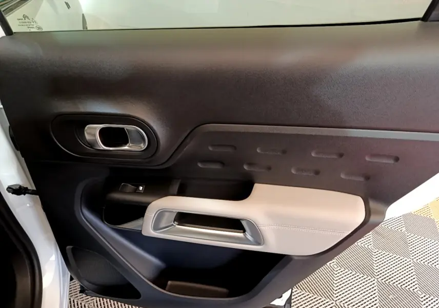 Gros plan sur la porte intérieure côté gauche du Citroën C5 Aircross Hybrid blanc, avec accoudoir beige et poignée argentée.