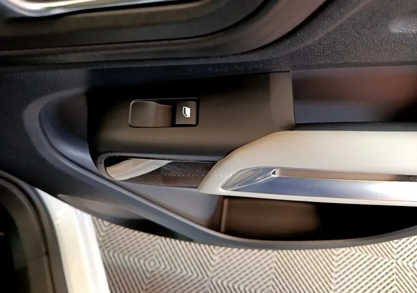 Gros plan sur la commande de lève-vitre côté conducteur de la porte intérieure noire et beige d'un Citroën C5 Aircross blanc.