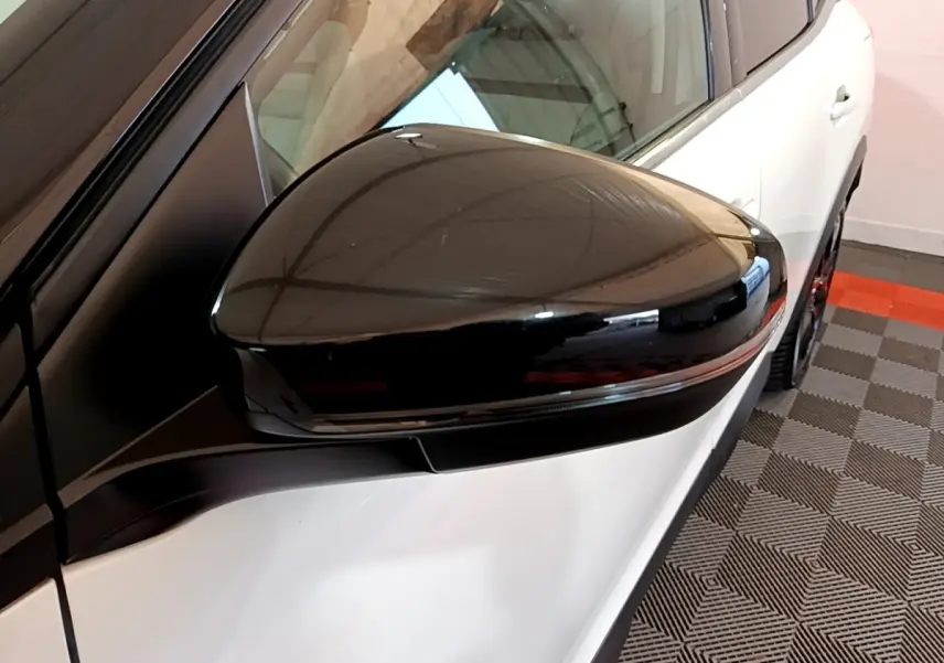 Gros plan sur le rétroviseur noir côté gauche d’un Citroën C5 Aircross Hybrid blanc, avec partie avant visible.