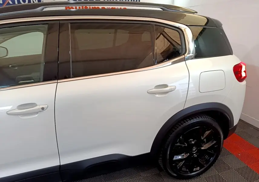Vue côté droit arrière du Citroën C5 Aircross Hybrid blanc avec toit noir et jantes noires brillantes.