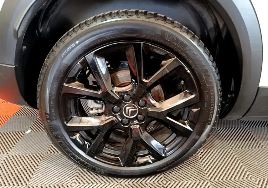 Gros plan sur la roue avant droite noire brillante du Citroën C5 Aircross blanc hybride rechargeable.