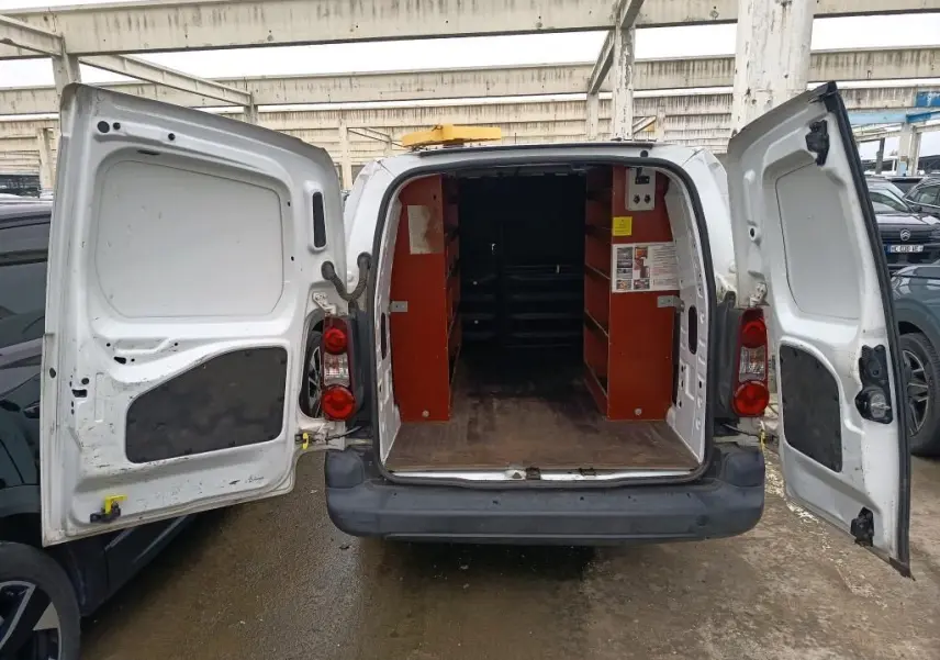 Vue arrière d’un Citroën Berlingo XL blanc 2018 avec portes ouvertes montrant l’intérieur utilitaire aménagé et un gyrophare jaune sur le toit.