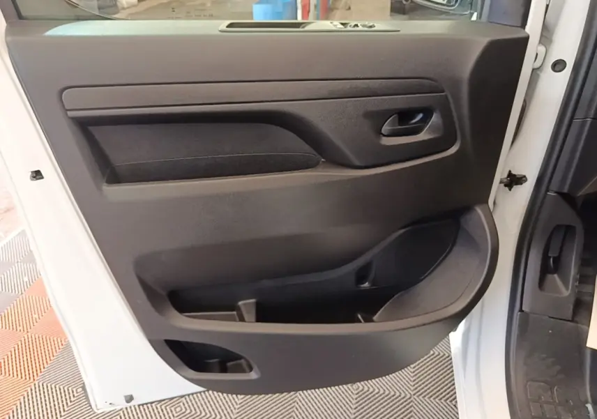 Vue intérieure côté gauche de la porte avant blanche du Peugeot Expert Fourgon avec panneau noir et rangements intégrés.