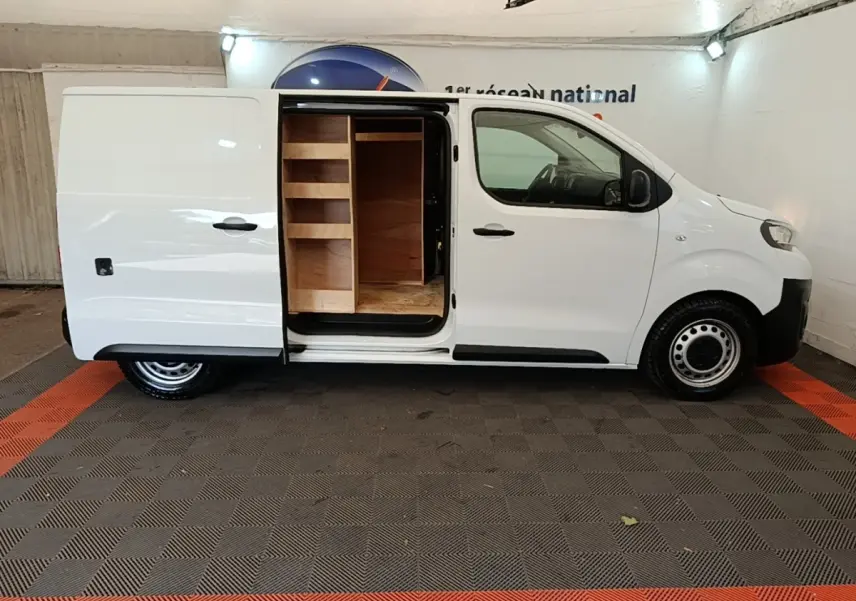 Vue latérale droite d’un Peugeot Expert Fourgon blanc 2023 avec porte coulissante ouverte révélant un aménagement bois intérieur.