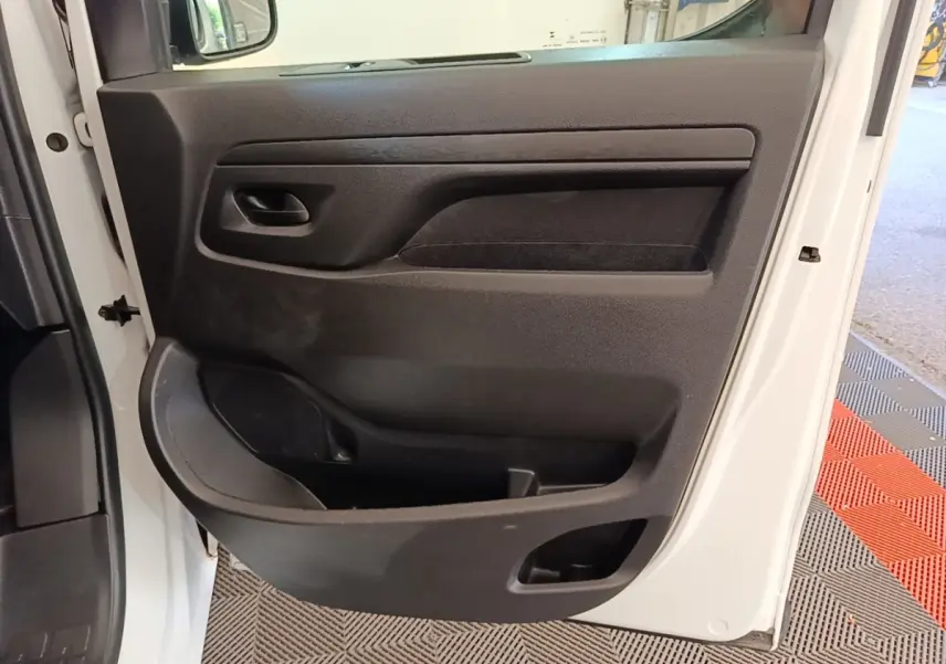 Vue rapprochée de la porte avant gauche ouverte du Peugeot Expert Fourgon blanc, montrant la garniture intérieure noire.