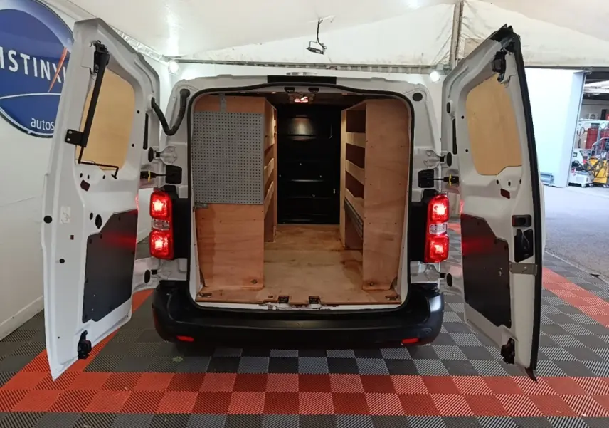 Vue arrière du Peugeot Expert Fourgon blanc 2023 avec portes ouvertes et aménagements bois dans l’espace de chargement.