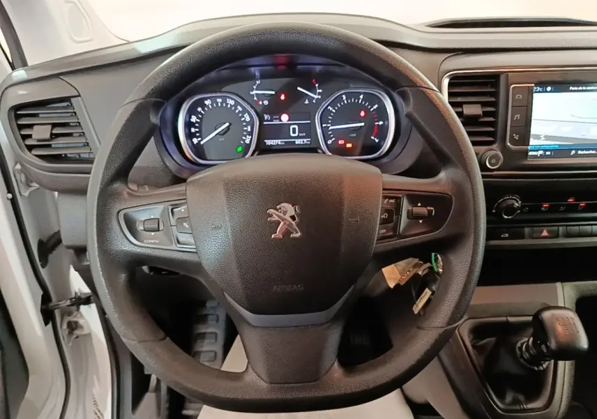 Vue intérieure centrée sur le volant Peugeot noir et le tableau de bord avec écran tactile du Expert Fourgon blanc.