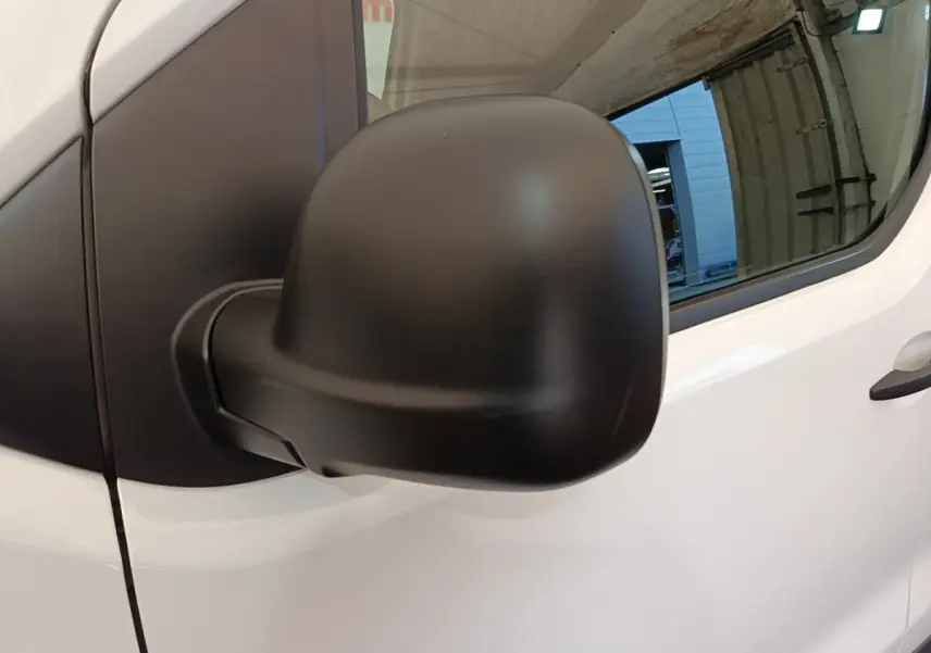 Gros plan sur le rétroviseur noir côté droit du Peugeot Expert Fourgon blanc, avec vitre et porte avant visibles.