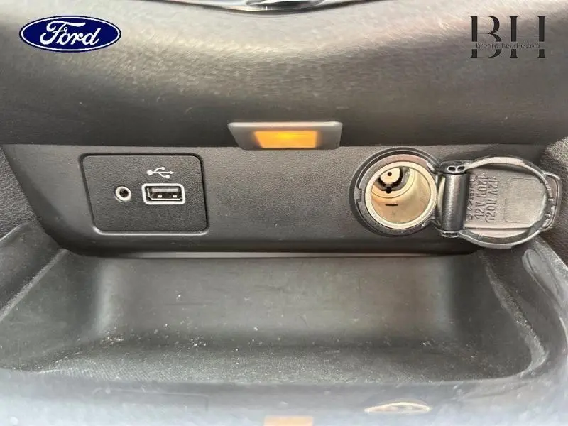 Prise USB, prise jack et allume-cigare ouverts sur la console centrale d'un véhicule, vue rapprochée.