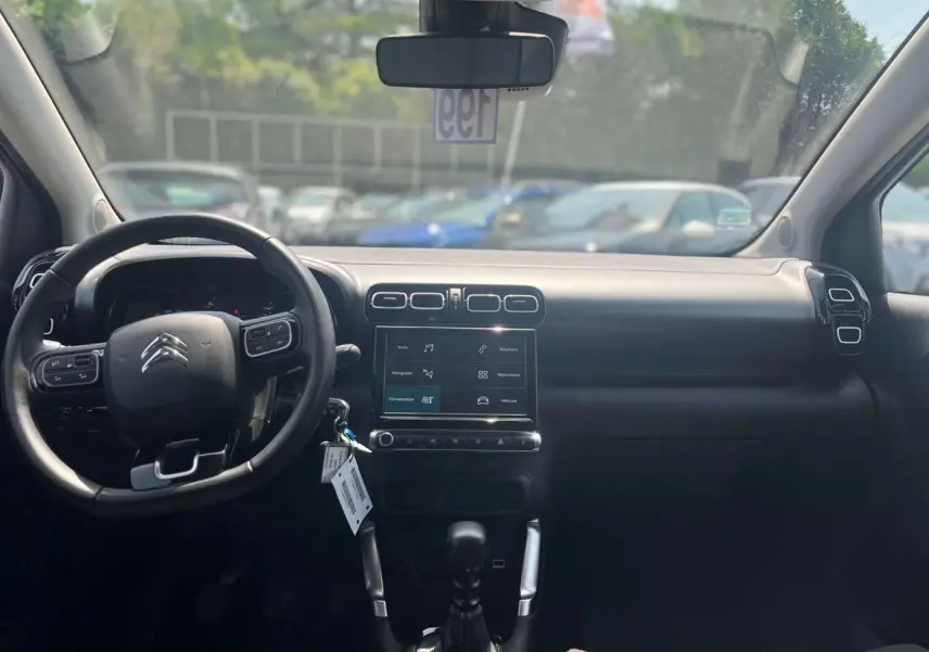 Vue intérieure frontale du tableau de bord noir du Citroën C3 Aircross 2023 avec volant multifonction et écran tactile central.