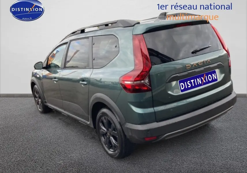 Vue 3/4 arrière droite d'un Dacia Jogger vert cèdre avec barres de toit et jantes noires.