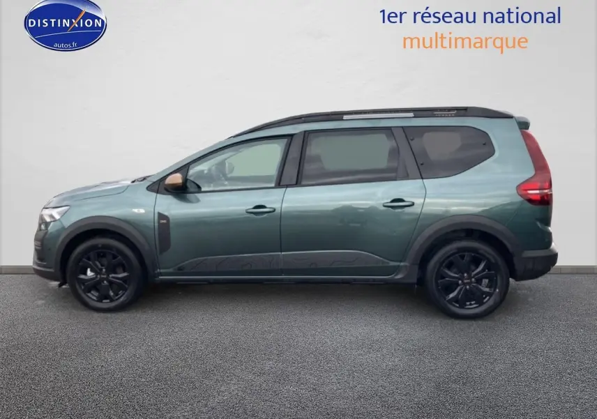 Vue de profil côté gauche d'un Dacia Jogger vert cèdre avec jantes noires et barres de toit.
