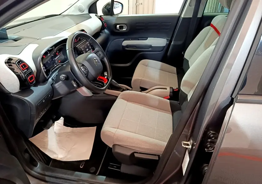 Vue intérieure côté conducteur de la Citroën C3 Aircross gris foncé, sièges tissu beige et volant cuir multifonctions.