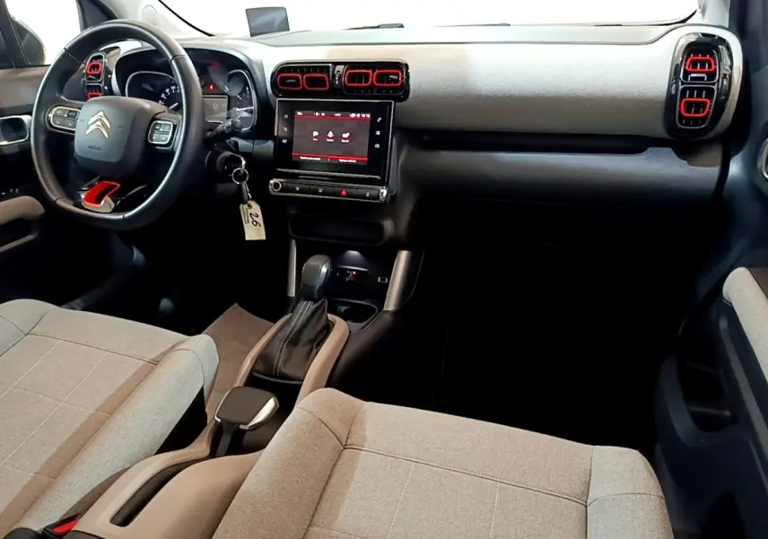 Vue intérieure avant droite du Citroën C3 Aircross 2020, tableau de bord noir avec touches rouges et sièges tissu gris clair.