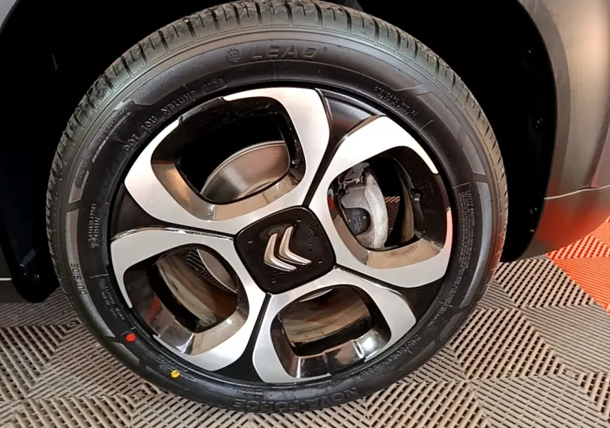 Gros plan sur la roue avant droite d'une Citroën C3 Aircross gris foncé avec jante alliage bicolore.