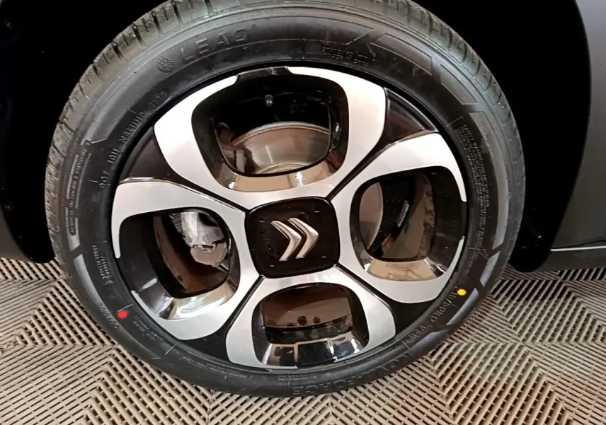 Gros plan sur la jante avant droite noire et argentée du Citroën C3 Aircross gris foncé, avec logo Citroën central.