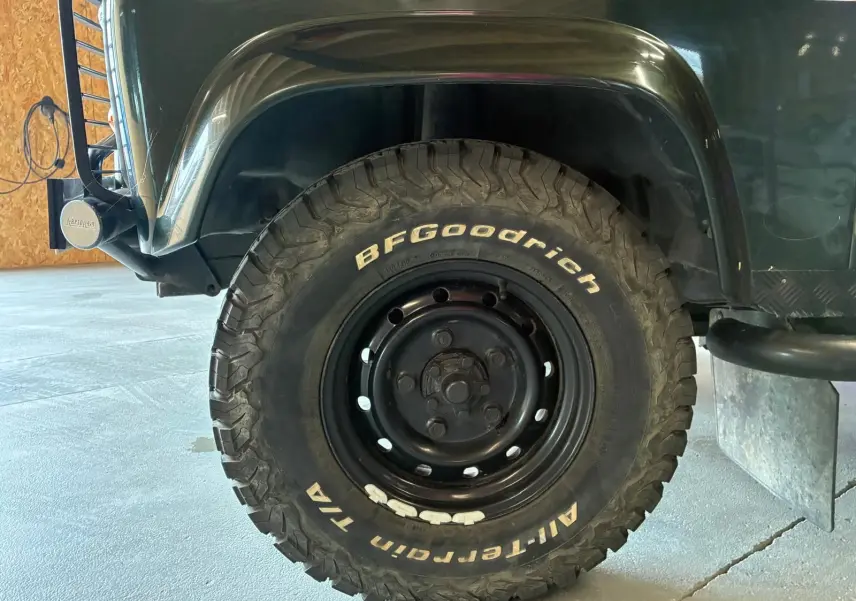 Gros plan sur la roue avant droite d’un Land Rover Defender 110 vert 2005 avec pneu BFGoodrich tout-terrain.