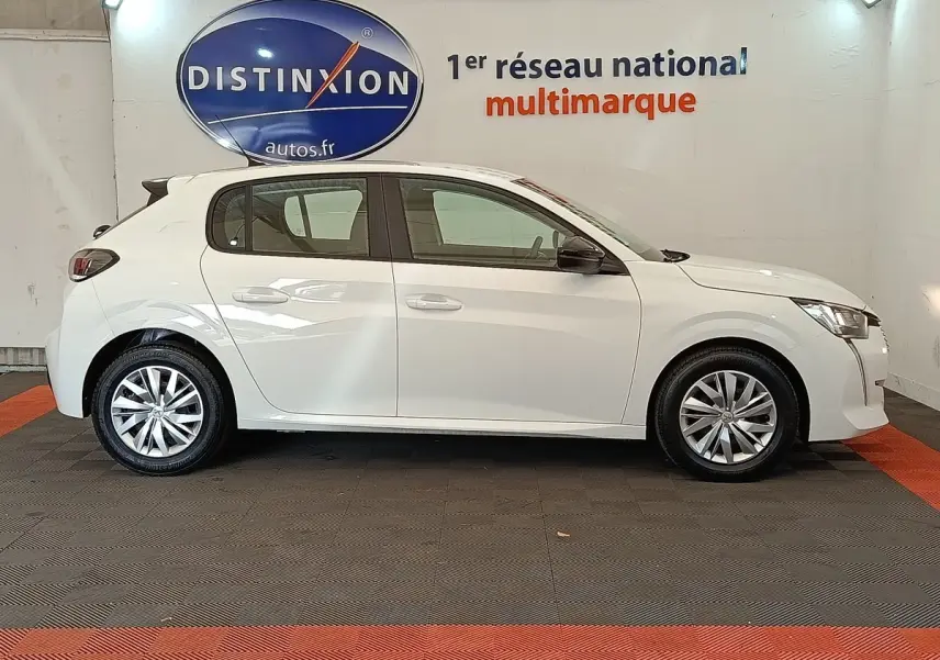 Profil côté gauche d'une Peugeot 208 blanche 2022 BlueHDi 100 S&S Active en intérieur, avec jantes alliage et rétroviseurs noirs.