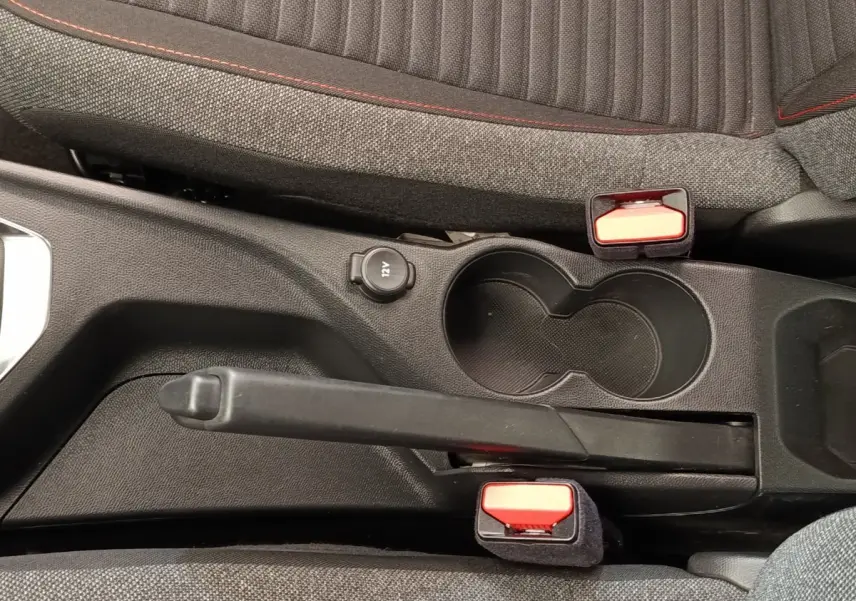 Vue rapprochée de la console centrale de la Peugeot 208 blanche, avec frein à main manuel et porte-gobelets noirs.