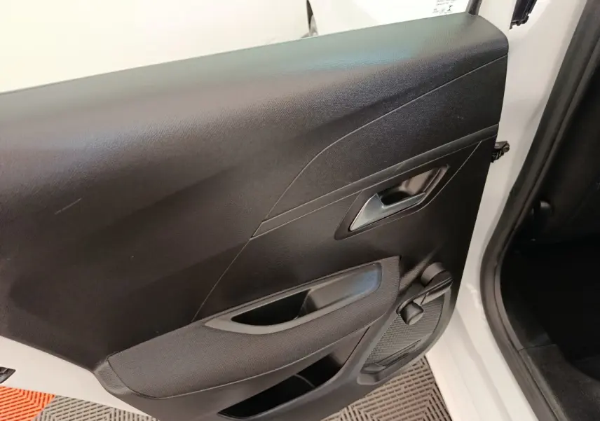 Vue rapprochée de la porte arrière droite noire avec poignée et manivelle de vitre d'une Peugeot 208 blanche.
