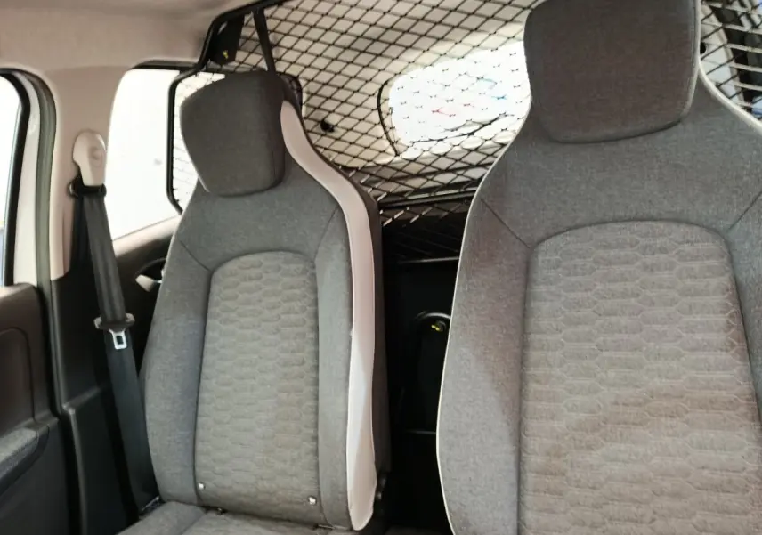 Vue intérieure avant des sièges gris de la Renault ZOE électrique avec séparation grillagée derrière les sièges.