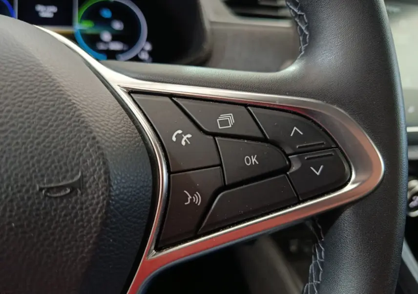 Gros plan sur les commandes multifonctions du volant en cuir synthétique noir de la Renault ZOE blanche 2023.